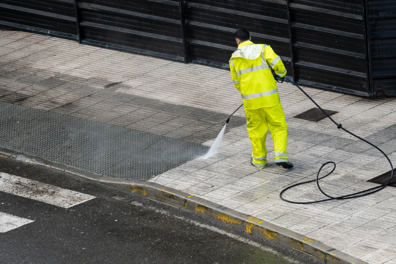 Worker cleaning the sidewalk with pressurized water